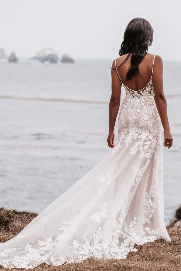 Een elegante trouwjurk van Allure Bridals met een V-hals en subtiele spaghettibandjes. De jurk heeft een prachtig kanten lijfje dat naadloos overgaat in een luchtige, vloeiende rok met bloemendetails en een elegante sleep. Perfect voor een bruiloft aan het strand of in een romantische buitenomgeving.