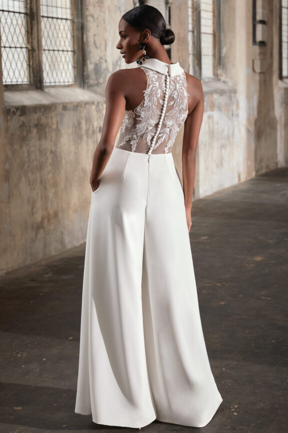 Elegante trouw-jumpsuit van het merk Justin Alexander - Adore, met een diepe V-hals en een transparante rug versierd met verfijnde kanten bloemenapplicaties.